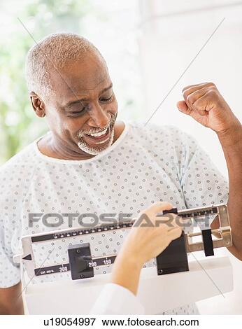 Stock Photo - Happy man on weight scale. Fotosearch