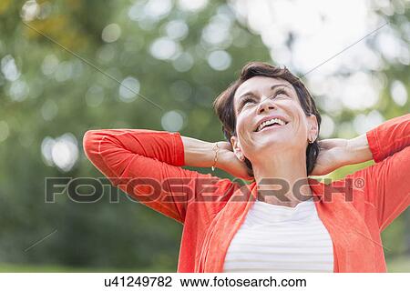 Happy mature woman raising hands in park View Large Photo Image Stock Image - Happy mature woman raising hands in park. Fotosearch