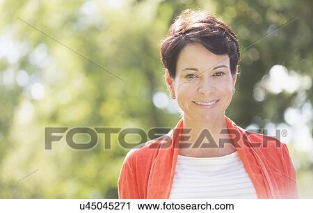 Happy mature woman raising hands in park View Large Photo Image Stock Image - Happy mature woman raising hands in park. Fotosearch