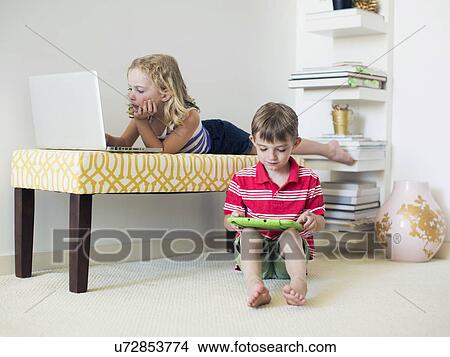 Kids (4-5, 6-7) using laptop and digital tablet indoors View Large Photo Image Picture - Kids (4-5, 6-7) using laptop and digital tablet indoors. Fotosearch