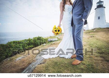 Picture - Low section of married couple, lighthouse in background. Fotosearch