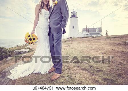 Stock Image - Low section of married couple, lighthouse in background. Fotosearch