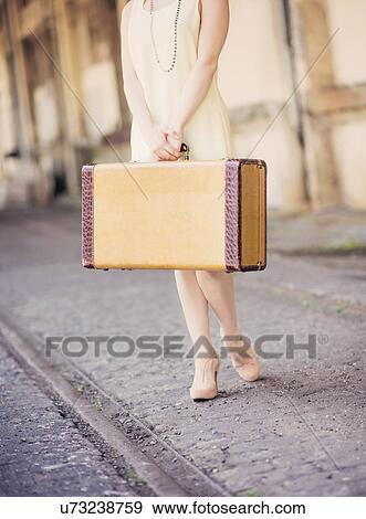 Low section of woman in dress holding suitcase at train station View Large Photo Image Stock Photo - Low section of woman in dress holding suitcase at train station. Fotosearch