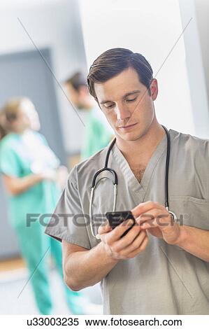 Stock Photography - Male doctor texting on phone. Fotosearch