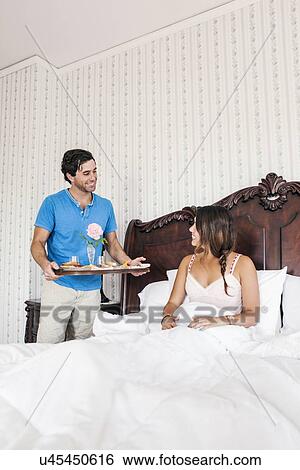 Man bringing woman breakfast to bed in hotel room View Large Photo Image Stock Photograph - Man bringing woman breakfast to bed in hotel room. Fotosearch