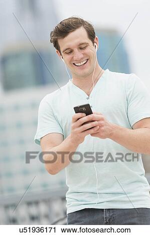 Stock Image - Man listening to music on smartphone. Fotosearch