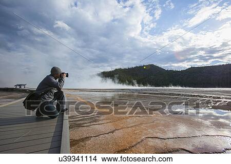 Picture - Man photographing Grand Prismatic Geyser . Fotosearch