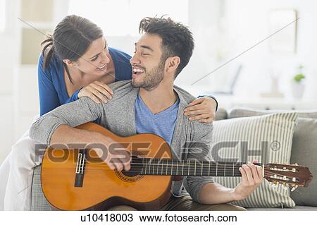 Man playing guitar while woman embracing him View Large Photo Image Stock Image - Man playing guitar while woman embracing him. Fotosearch