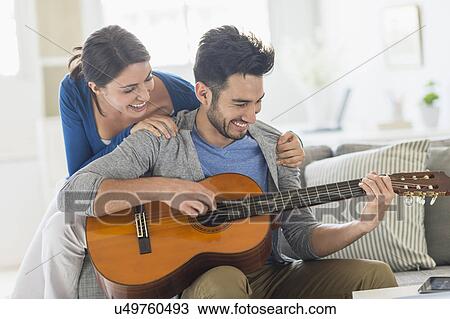 Man playing guitar while woman embracing him View Large Photo Image Stock Image - Man playing guitar while woman embracing him. Fotosearch