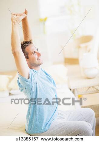 Man sitting on bed and stretching View Large Photo Image Stock Photo - Man sitting on bed and stretching. Fotosearch