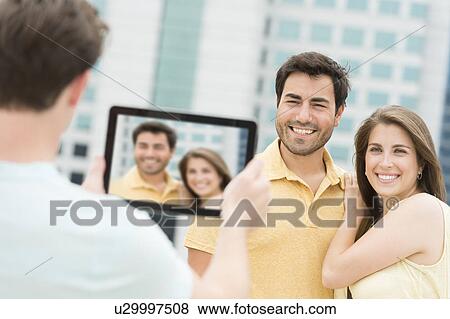 Man using tablet pc to take picture of friends View Large Photo Image Stock Photo - Man using tablet pc to take picture of friends. Fotosearch