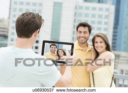 Man using tablet pc to take picture of friends View Large Photo Image Stock Photo - Man using tablet pc to take picture of friends. Fotosearch