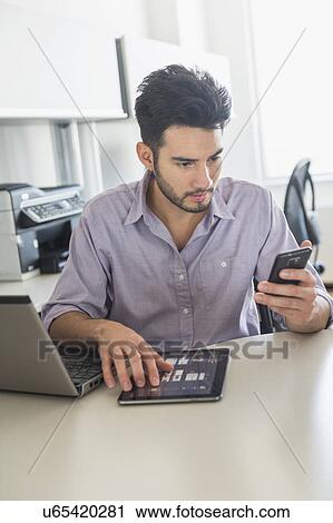 Stock Image - Man using technology in office. Fotosearch