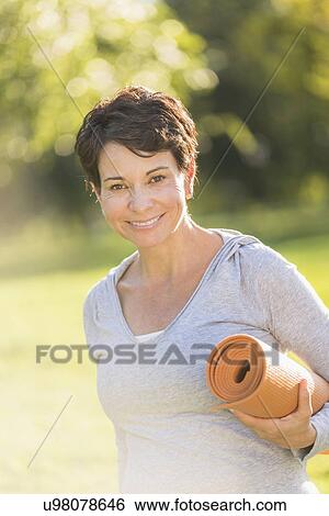 Mature woman holding yoga mat outdoors View Large Photo Image Stock Photograph - Mature woman holding yoga mat outdoors. Fotosearch