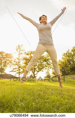 Mature woman jumping on grass View Large Photo Image Picture - Mature woman jumping on grass. Fotosearch