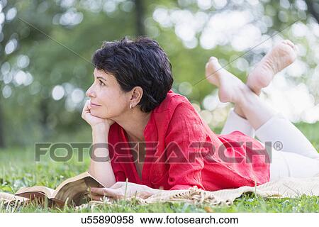 Mature woman lying on grass and reading book View Large Photo Image Stock Photo - Mature woman lying on grass and reading book. Fotosearch
