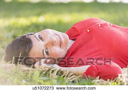 Stock Image - Mature woman lying on grass. Fotosearch