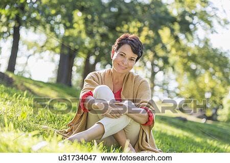 Mature woman sitting on grass in park View Large Photo Image Stock Photo - Mature woman sitting on grass in park. Fotosearch