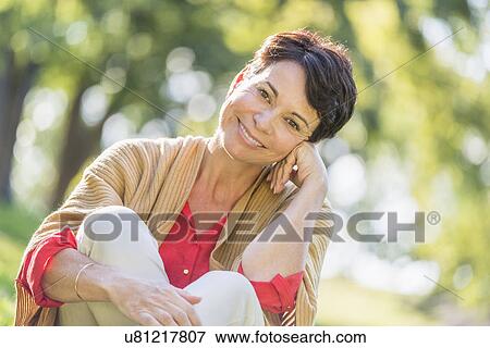 Mature woman sitting on grass in park View Large Photo Image Stock Photo - Mature woman sitting on grass in park. Fotosearch