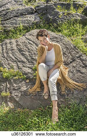 Mature woman sitting on rock View Large Photo Image Stock Image - Mature woman sitting on rock. Fotosearch
