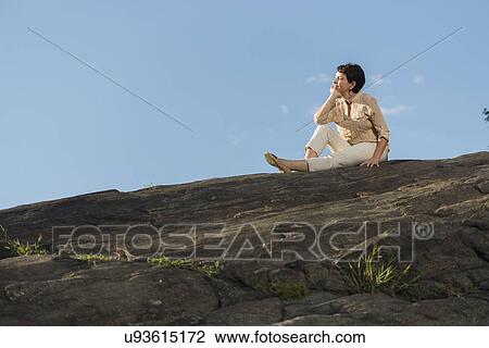 Mature woman sitting on rock View Large Photo Image Stock Image - Mature woman sitting on rock. Fotosearch