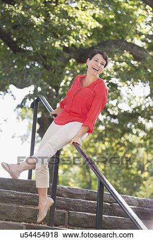 Stock Photo - Mature woman sliding down railing in park. Fotosearch