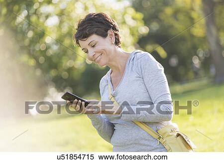 Mature woman text messaging outdoors View Large Photo Image Stock Photography - Mature woman text messaging outdoors. Fotosearch