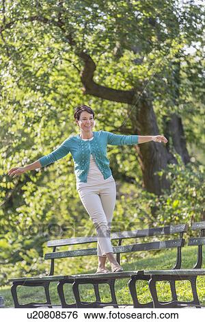 Mature woman walking on bench View Large Photo Image Stock Photograph - Mature woman walking on bench. Fotosearch