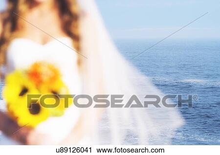 Mid section of bride holding sunflower bouquet, sea in background View Large Photo Image Stock Image - Mid section of bride holding sunflower bouquet, sea in background. Fotosearch