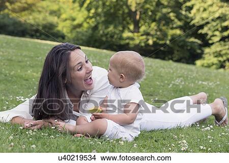 Mother and daughter (12-17 months) playing in park View Large Photo Image Picture - Mother and daughter (12-17 months) playing in park. Fotosearch