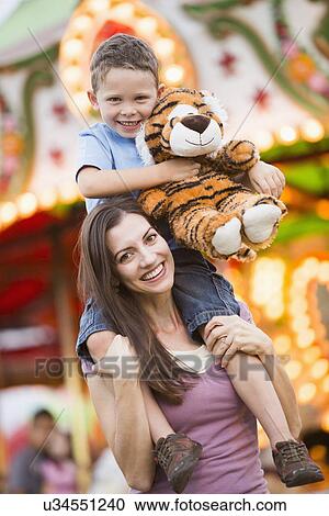 Mother giving her son (4-5) piggyback ride in amusement park View Large Photo Image Stock Image - Mother giving her son (4-5) piggyback ride in amusement park. Fotosearch