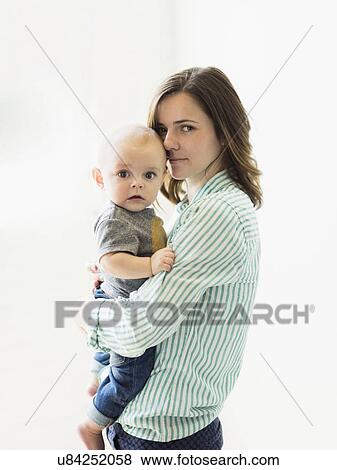 Stock Photo - Mother holding baby boy (6-11 months) indoors. Fotosearch