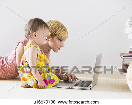 Stock Photo - Mother with baby daughter (12-17 months) using laptop. Fotosearch