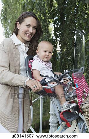 Stock Photo - Mother with her baby daughter (12-17 months) on bicycle. Fotosearch