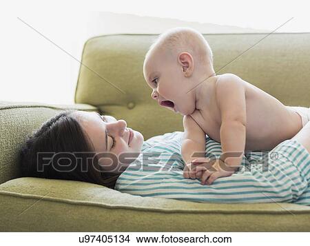 Picture - Mother with son (6-11 months) lying on sofa. Fotosearch