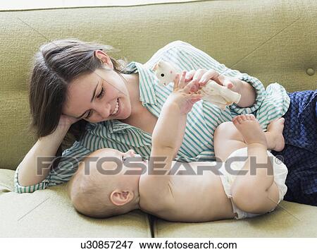 Stock Photo - Mother with son (6-11 months) lying on sofa. Fotosearch