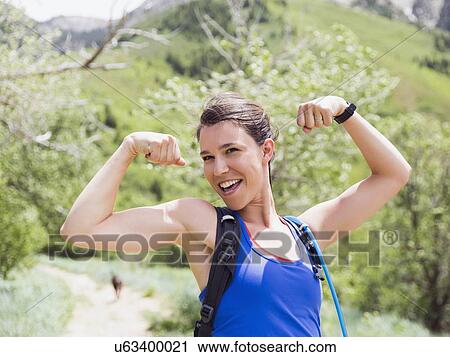 Stock Image - Portrait of athletic woman flexing muscles. Fotosearch