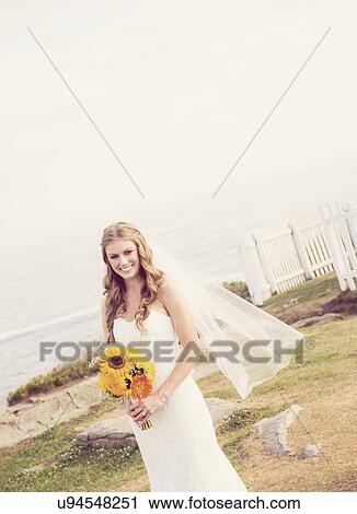 Stock Image - Portrait of bride holding sunflower bouquet. Fotosearch