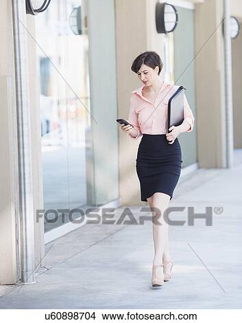 Portrait of business woman walking and text messaging View Large Photo Image Picture - Portrait of business woman walking and text messaging. Fotosearch