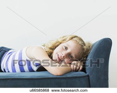 Stock Photo - Portrait of girl (4-5) lying on bench indoors. Fotosearch