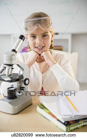 Stock Photo - Portrait of girl (8-9) with microscope. Fotosearch