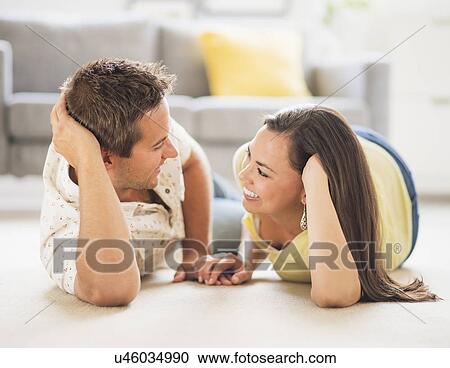 Stock Image - Portrait of happy couple lying on side, face to face. Fotosearch