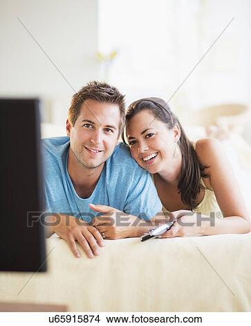 Picture - Portrait of happy couple watching TV. Fotosearch
