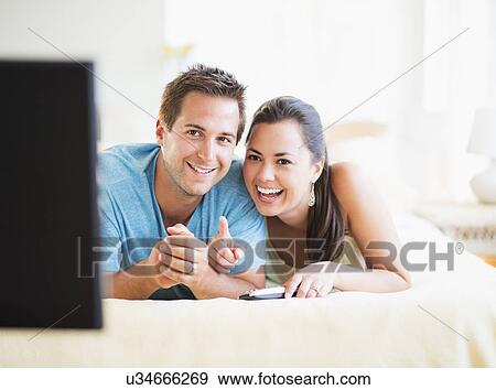 Portrait of happy couple watching TV View Large Photo Image Stock Photo - Portrait of happy couple watching TV. Fotosearch