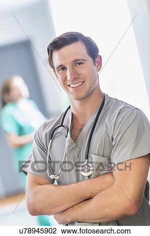 Stock Image - Portrait of male doctor in hospital hallway. Fotosearch