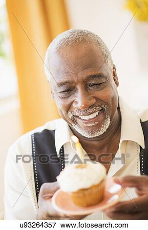 Portrait of man holding cupcake with candle View Large Photo Image Stock Photo - Portrait of man holding cupcake with candle. Fotosearch