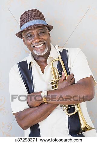 Stock Image - Portrait of man holding trumpet. Fotosearch
