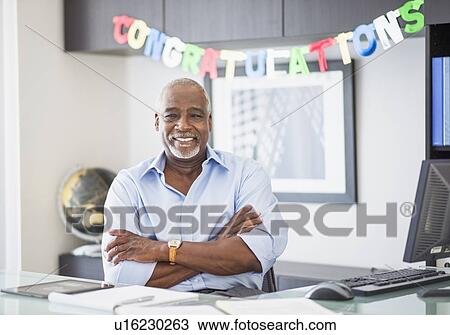 Stock Image - Portrait of man in office, congratulations sign behind. Fotosearch