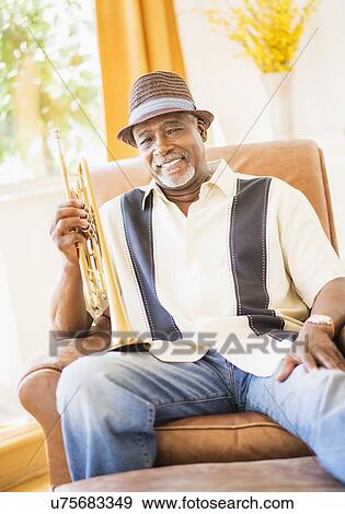 Portrait of man sitting in armchair and holding trumpet View Large Photo Image Stock Photo - Portrait of man sitting in armchair and holding trumpet. Fotosearch