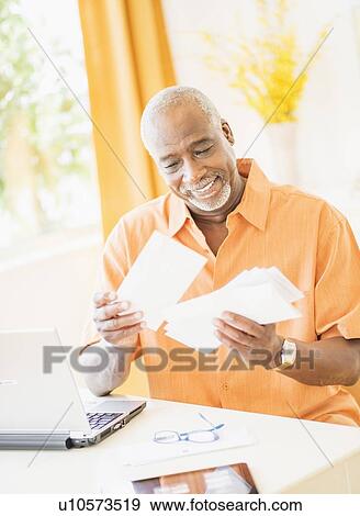 Portrait of man sorting mail at home View Large Photo Image Stock Photo - Portrait of man sorting mail at home. Fotosearch